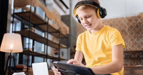 Image of a student in a yellow shirt working in an online class on a tablet at Connections Academy